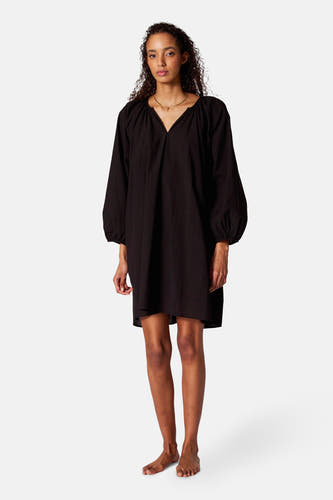 Robe noire avec manches longues de SUNSET STUDIO, avec col V et chaîne d'or.