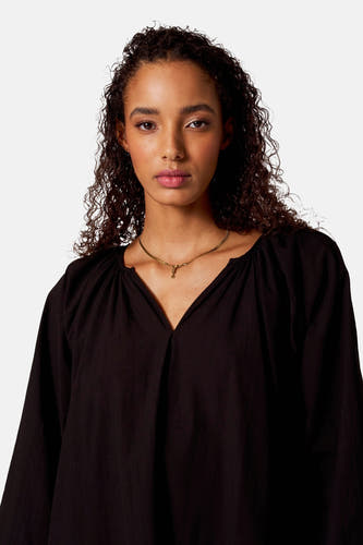 Robe noire à longues manches de SUNSET STUDIO, avec un col V et des détails plissés.