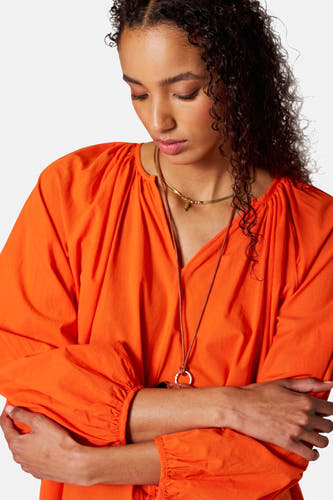 Maillot orange à longues manches de SUNSET STUDIO, avec une coupe décontractée et des chaînes d'or.