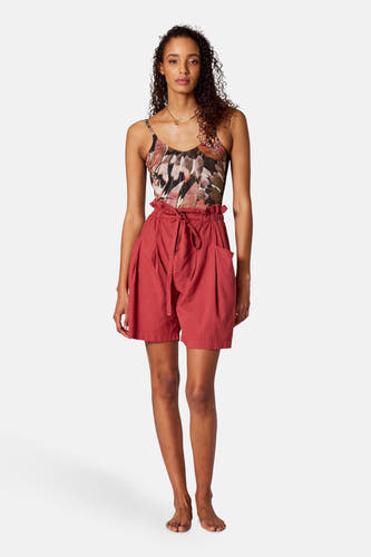 Paquet de bain multicolore de SUNSET STUDIO, avec un motif de feuille et porté avec des shorts rouges à ceinture élastique.