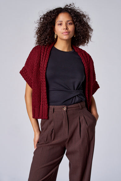 Gilet parme d'Astrid Black Label, avec une texture grossière tr tricotée, porté sur une chemise noire et un pantalon marron.