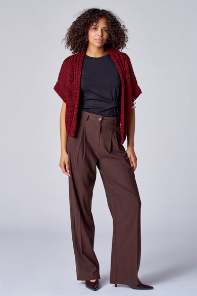 Gilet parme d'Astrid Black Label, porté sur une chemise noire et un pantalon marron.