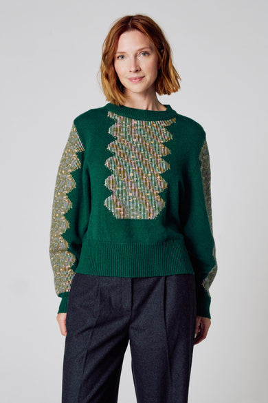 T-shirt vert avec col rond de Clouds of Fashion, avec un motif géométrique et porté avec un pantalon gris foncé.