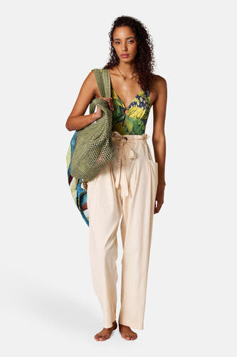 Pantalon beige de SUNSET STUDIO, avec taille paperbag et détail de cordon, associé à un sac en tissu vert.
