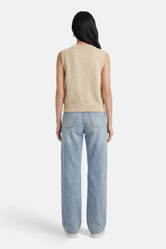 Pull beige ADORE, à col rond et sans manches, combiné avec un jean bleu clair et des chaussures blanches.