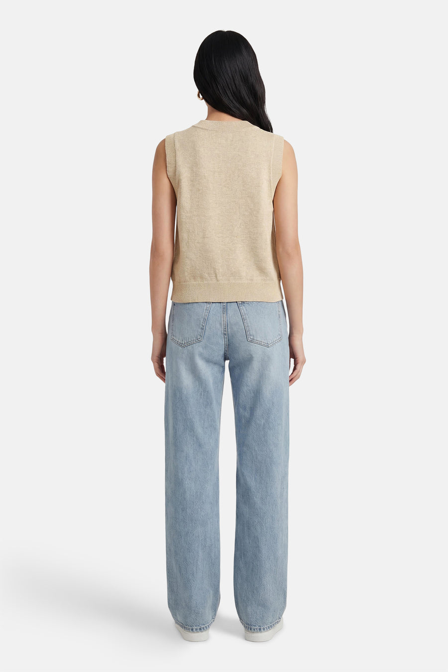 Pull beige ADORE, à col rond et sans manches, combiné avec un jean bleu clair et des chaussures blanches.