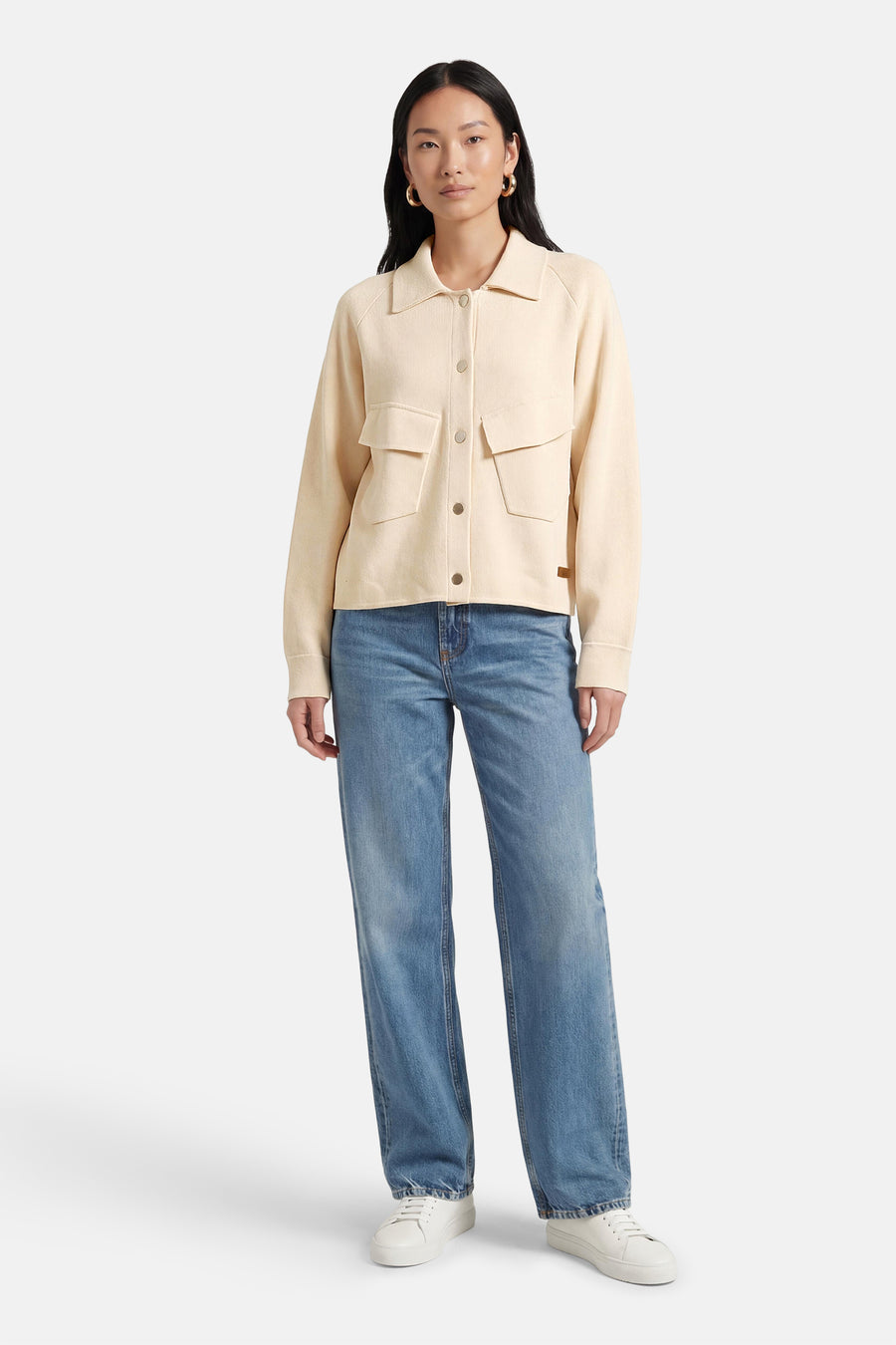 Gilet écru ADORE, à manches longues, fermeture boutonnée et poches plaquées, combiné avec un jean bleu et des baskets blanches.