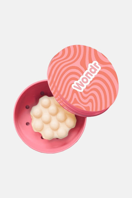 Produit de soin multicolore WONDR CARE, dans un récipient rose avec des billes et un couvercle illustré.