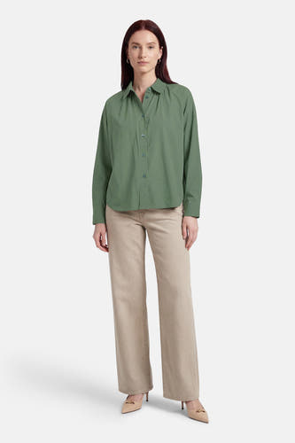 Chemise verte ADORE, à manches longues, portée avec un pantalon beige et des escarpins.