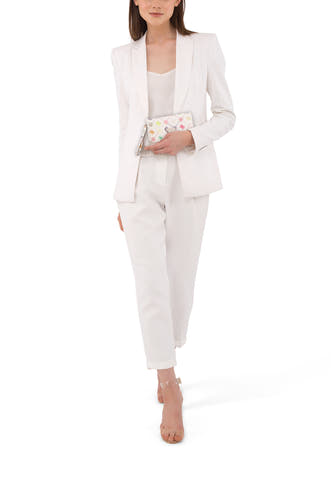 Portefeuille multicolore Guess à motif et dragonne, assortie à un pantalon blanc pour femme et un blazer.
