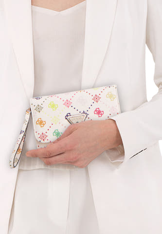 Portefeuille multicolore pour femme Guess avec divers motifs et dragonne, portée par un mannequin dans une tenue blanche.