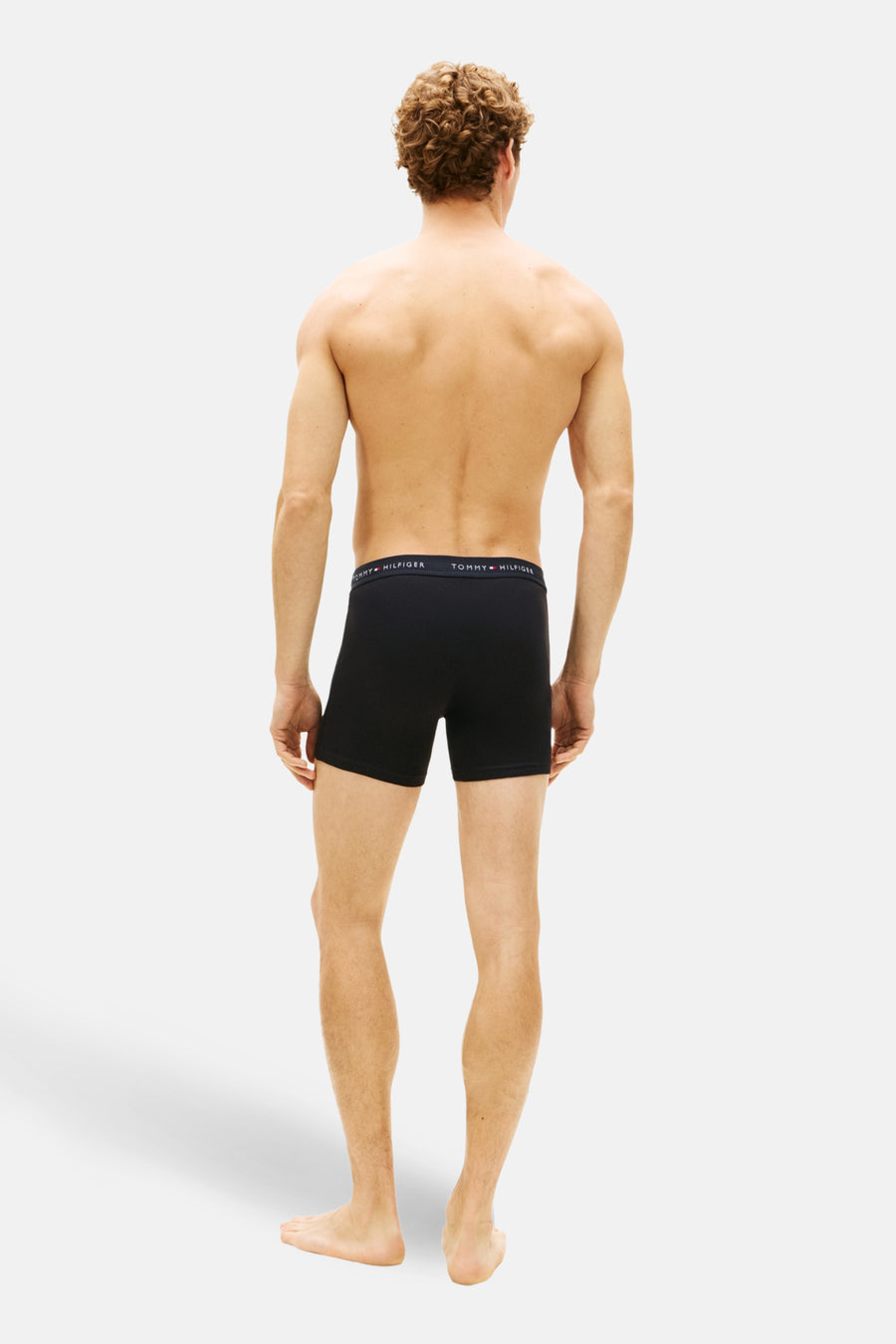 Man van achteren, zwarte Tommy Hilfiger boxershort.
