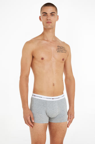 Boxer short gris de TOMMY JEANS, porté par un homme avec un tatouage sur la poitrine.