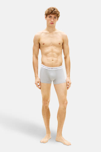 Boxer short gris Tommy Hilfiger porté par un homme musclé sur un fond blanc.