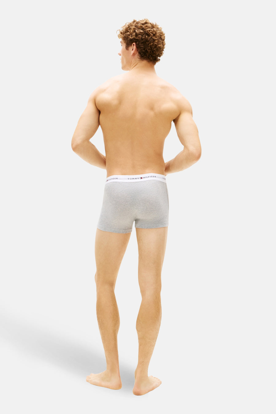 Man met ontbloot bovenlijf, grijze Tommy Hilfiger-boxershorts.