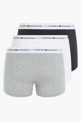 Trois boxershorts de Tommy Jeans en gris, blanc et noir, empilés sur un fond blanc.