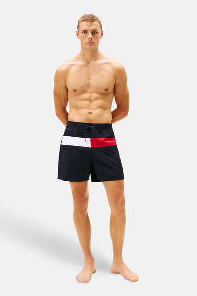 Blauwe zwemshort van Tommy Jeans met een rode en witte streep, gedragen door een model.
