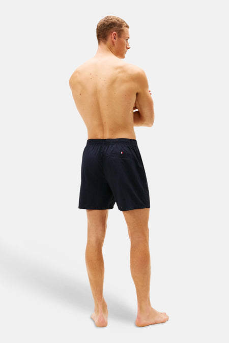 Short de bain bleu de TOMMY JEANS, vu de dos, avec un petit drapeau logo sur la poche arrière.