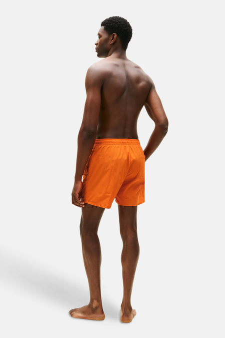 Short de bain orange Tommy Hilfiger, vu de dos sur un homme au dos nu.