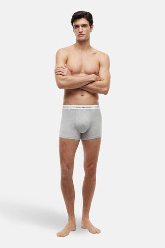 Boxer short gris de TOMMY JEANS, porté par un homme les bras croisés et pieds nus.