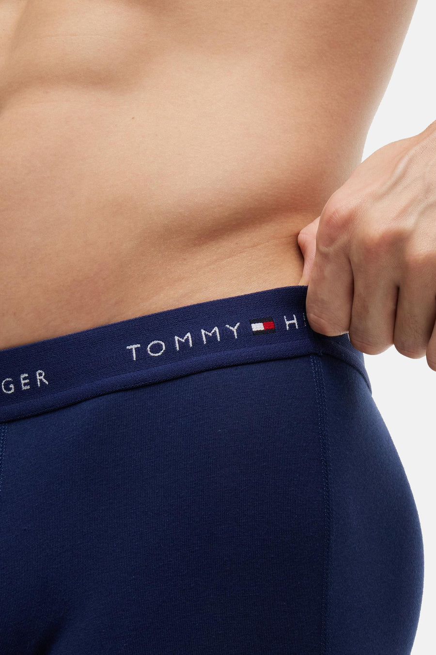 Donkerblauwe boxershort met witte TOMMY JEANS logo op tailleband, close-up van model van achteren