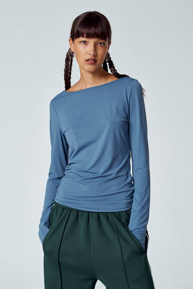 T-shirt bleu à manches longues d'Unwind, avec une coiffure tressée et un pantalon vert.