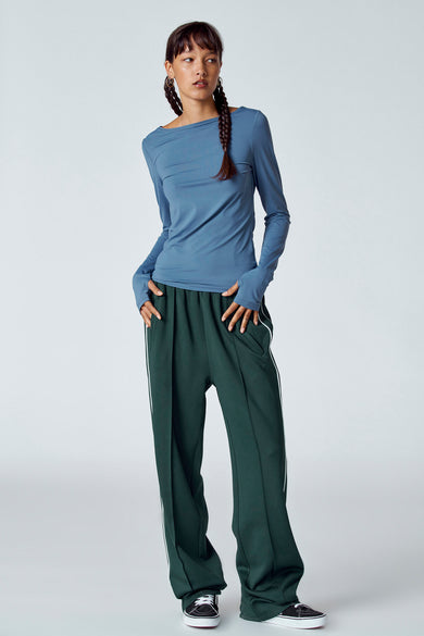 T-shirt bleu à manches longues d'Unwind, porté avec un pantalon vert et des chaussures noires.