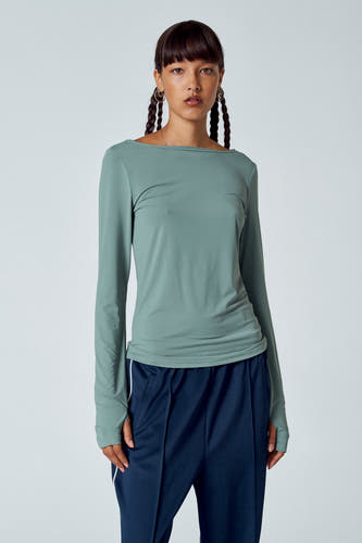 T-shirt vert avec manches longues d'Unwind, avec des poches et un short sportif à rayures blanches.