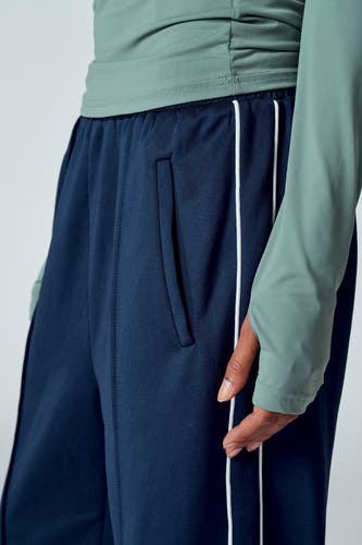 T-shirt vert avec manches longues d'Unwind, associé à un pantalon bleu avec des rayures blanches.