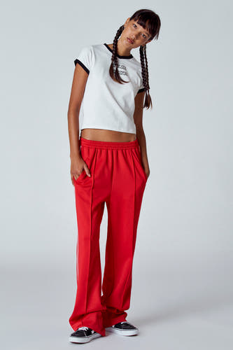 T-shirt blanc à manches courtes et col noir d'Unwind, avec imprimé sur la poitrine, associé à une jupe rouge et des baskets.