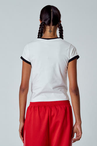 T-shirt blanc à manches courtes d'Unwind, avec des accents noirs sur la ligne du col et les manches ; porté avec un short rouge.