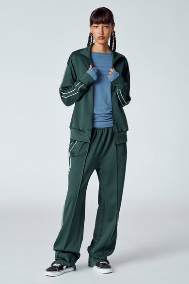 T-shirt sans manches vert d'Unwind, porté sous un maillot de corps vert avec des rayures blanches et des chaussures noires.