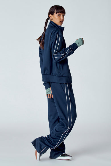 Gilet bleu à manches courtes d'Unwind, avec une bande blanche le long du côté et porté avec des vêtements de sport.