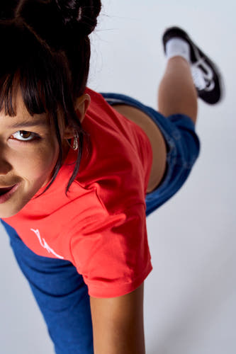 T-shirt rouge à manches courtes de Unwind, porté avec un pantalon bleu et des chaussures noires, vue du haut.