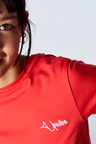 T-shirt rouge à manches courtes de Unwind, avec des détails brodés et porté par un modèle.