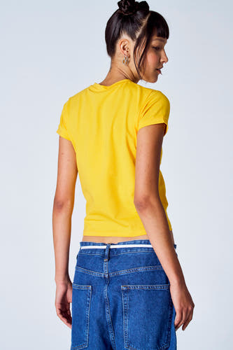 T-shirt jaune à manches courtes de Unwind, porté avec un jean bleu à haut tailleur.