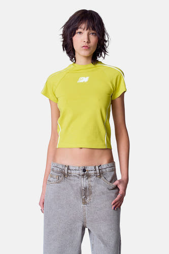 T-shirt vert avec manches courtes d'Unwind, avec des accents blancs et porté avec un jean gris.