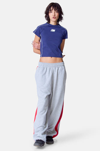 T-shirt bleu à manches courtes d'Unwind, avec une patte blanche sur le côté et porté avec un short de jogging gris.