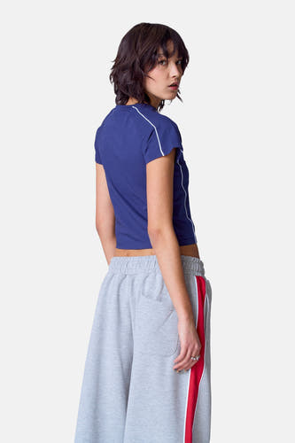 T-shirt bleu à manches courtes d'Unwind, vu de derrière, avec des rayures blanches et porté avec un short de jogging gris.