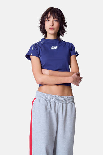 T-shirt bleu à manches courtes d'Unwind, avec un col blanc sur les manches et un logo sur la poitrine.