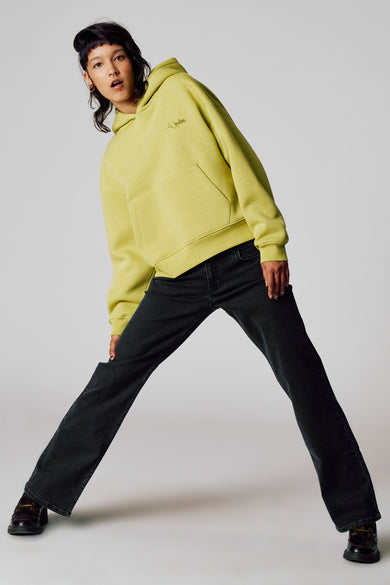 Pull-over vert de Unwind avec capuche, porté avec des jeans foncés et des loafers en cuir.