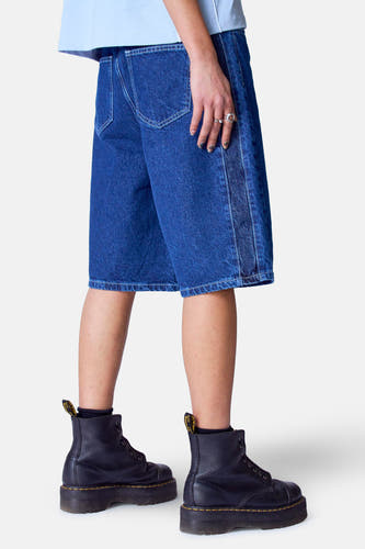 Short en denim bleu marine d'Unwind, avec une taille haute et une styling avec des bottes noires.