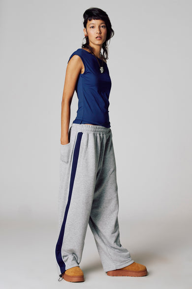 Vrouw in blauwe top en grijze joggingbroek met blauwe streep.