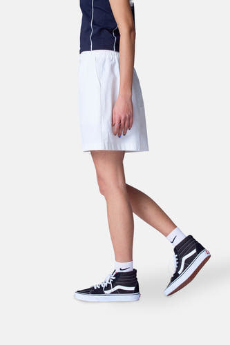 Short blanc d'Unwind, associé à un t-shirt bleu marine et des baskets Vans hautes avec des chaussettes blanches.