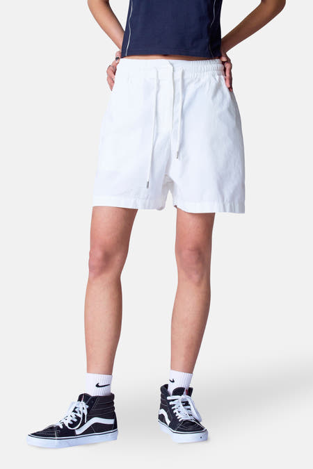 Short blanc d'Unwind, avec cordon et porté avec des baskets noires hautes et des chaussettes blanches.