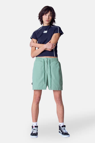 Short vert de Unwind, avec une corde et porté avec un t-shirt bleu foncé et des baskets noires hautes.