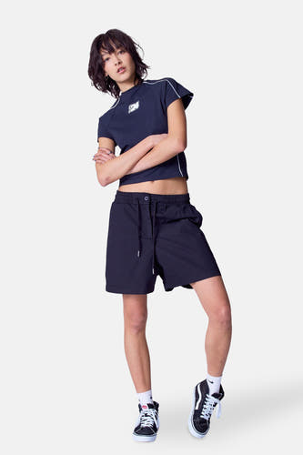 Short noir d'Unwind, avec cordon et porté avec un haut et des baskets hautes.