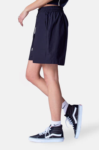 Short noir d'Unwind, avec une ceinture élastique et porté avec des baskets noires hautes et des chaussettes blanches.