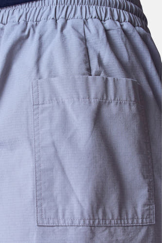 Veste grise d'Unwind, avec une ceinture élastique et une poche brodée, en gros plan.