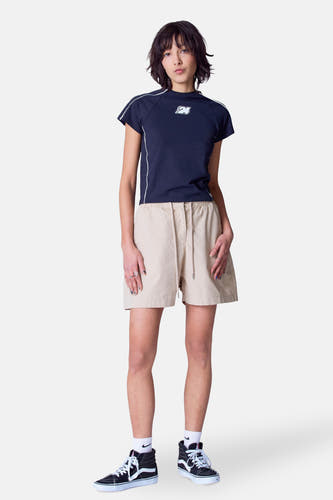 Beige court de Unwind, avec une corde et porté avec un t-shirt bleu foncé et des baskets noires.
